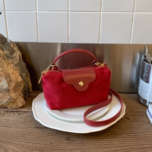 Close-up of deep red faux suede handbag showing mixed leather textures and gold hardware