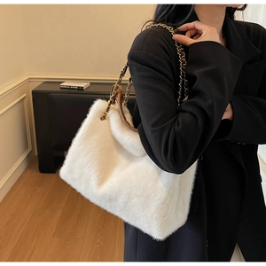Detail of white plush faux fur tote bag with brown handles and golden chain strap