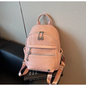 Pink lychee texture backpack with dual ring zippers and side chains on a sofa