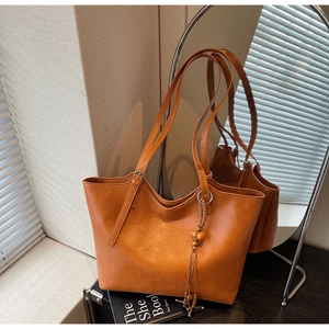 Detail of caramel vintage tote bag featuring wooden bead tassel and adjustable straps