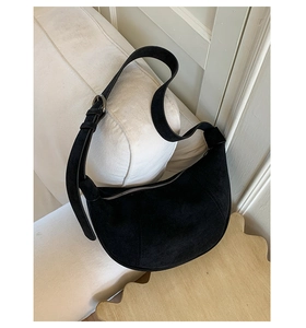 Dettaglio della borsa hobo in pelle scamosciata nera con fibbia in argento su divano