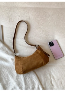 Vue détaillée du sac en daim marron avec boucle argentée et surpiqûres de précision