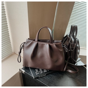 Close-up of dark brown pleated leather shoulder bag with grainy lychee texture details