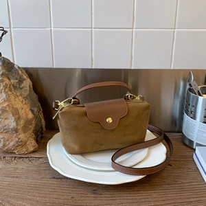Detail of suede and lychee leather textures on a brown mini handbag with gold hardware
