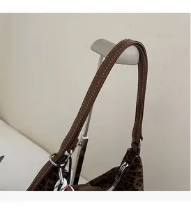 Detail view of brown faux leather handles with white stitching and silver metal hardware
