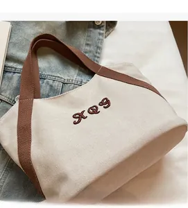 Close-up of canvas tote bag texture with embroidery and brown strap detail
