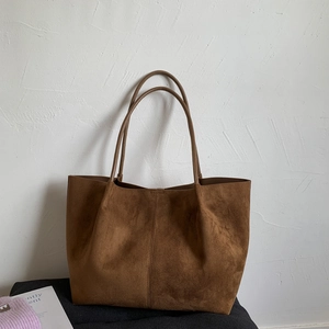 Detail shot of brown suede tote bag featuring slim shoulder straps and vertical seam