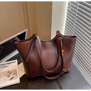Detail of dark brown tote bag with leather texture and wooden bead tassel decoration