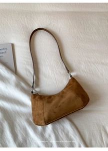 Détail d'un sac demi-lune en daim marron avec texture mate et boucles en argent fin