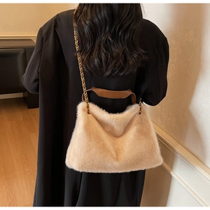 Detail of soft beige faux fur tote bag with brown leather handle and gold chain strap