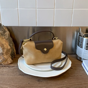 Close-up of contrast faux suede mini bag with premium stitching and gold metal hardware