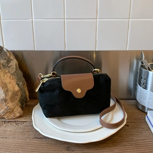 Detail of contrast suede and brown leather crossbody bag with gold hardware on a tray