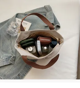 Top view of spacious canvas tote interior holding a wallet, cosmetics and phone