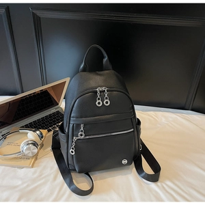 Detailed shot of a black litchi grain faux leather backpack on a minimalist background