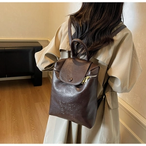 Détail du sac à dos vintage en similicuir marron avec lettrage embossé porté par un mannequin