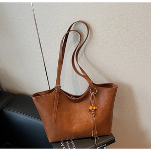 Detail of vintage brown tote bag with retro gourd tassel pendant on art magazine