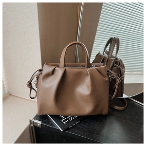 Close-up of brown pleated leather handbag detail with drawstring knot on the side