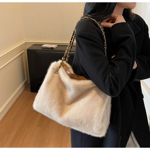 Detail view of large beige faux fur tote bag with brown leather trim and chain strap