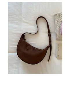 Detailed top view of dark coffee suede crescent bag on a white textured fabric background