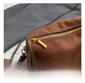 Close-up of golden metal zipper and dark brown suede texture on vintage crossbody bag