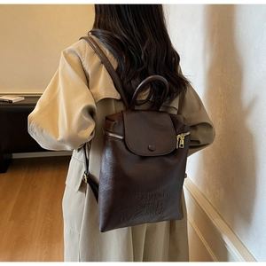 Détail du sac à dos vintage café montrant le cuir souple et le logo embossé