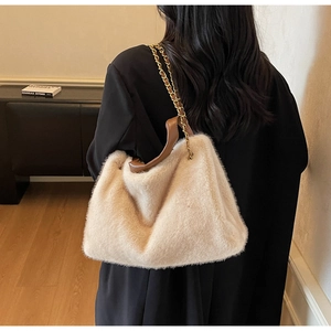 Detail view of beige faux fur tote bag with brown leather handle and gold chain strap