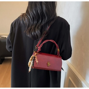Detail of burgundy vintage crossbody bag with wooden beads and golden metallic twist lock