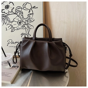 Detail of dark brown pleated leather handbag with elegant handle and detachable shoulder strap