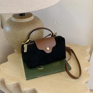 Detail of contrast stitching and lychee grain leather texture on the small suede crossbody bag