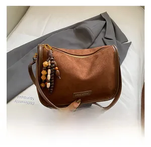Detail shot of brown suede crossbody bag with vintage wooden beads and golden logo plate