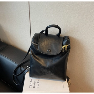 Détail du sac à dos en similicuir noir avec gaufrage de lettres et fermeture dorée