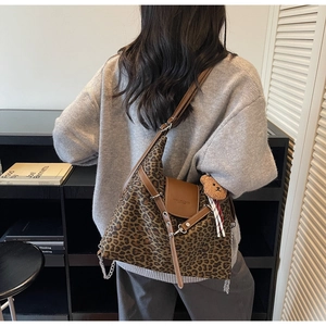 Detail of leopard print tote bag with brown leather trim and cute teddy bear charm