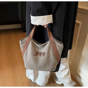 Detailed view of the durable canvas tote bag featuring premium brown handle and embroidery