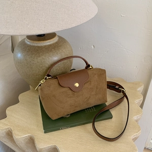 Close-up of contrast suede handbag with litchi grain flap and gold metal buckle