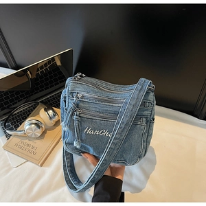 Detailed view of casual blue denim crossbody bag with multiple zipper compartments