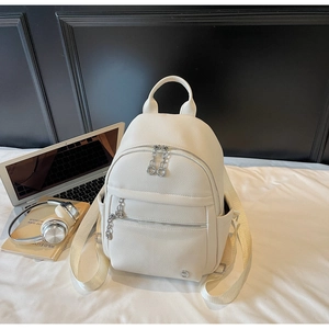 Close-up of white lychee pattern leather backpack with silver metal zippers and side pockets