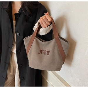 Close-up of khaki canvas tote bag featuring premium brown RQG embroidery and woven handles
