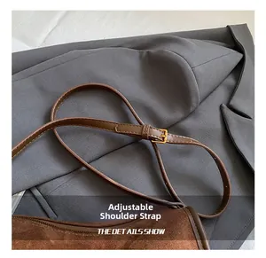 Detail of adjustable shoulder strap with gold buckle on brown matte leather crossbody bag