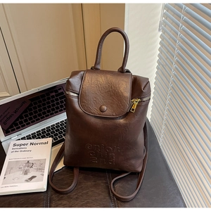 Détail d'un sac à dos en cuir marron avec ordinateur et livre sur un bureau moderne