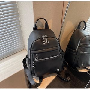 Detail of black pebbled leather backpack showing silver zippers and round metal pullers