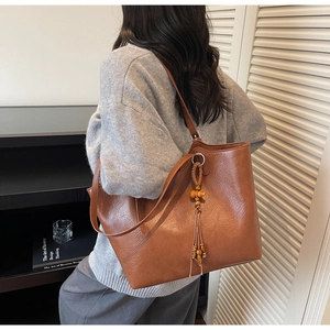 Brown vintage tote bag with lychee texture and woven wooden bead tassel on a shoulder strap