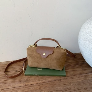 Detail of suede and leather patchwork handbag with metallic zipper and curved handle
