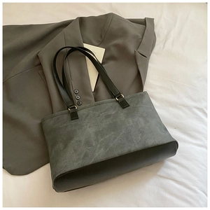 Detail of grey matte tote bag with black leather base and handles on white fabric