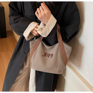 Close-up of brown canvas tote bag with XQG embroidery and wide strap handle