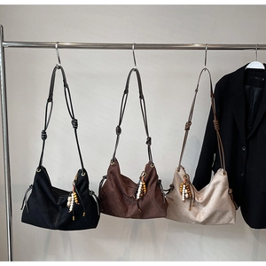 Detailansicht der Wildleder-Umhängetaschen in Schwarz, Braun und Beige mit Holzperlendekor