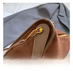 Detailed view of the gold metal hook and zipper on a brown frosted crossbody bag
