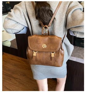 Detailed view of vintage brown leather backpack with gold twist lock and adjustable straps