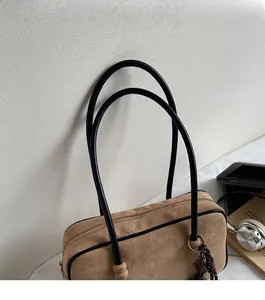 Detailed close-up of brown suede shoulder bag showing metal zipper and woven texture