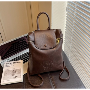 Détail d'un sac à dos marron foncé en similicuir avec texte en relief et fermeture éclair