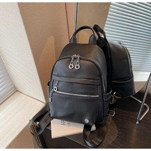 Detailed view of black pebble leather backpack with round metal zippers and side pockets